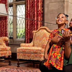 Mother and daughter smiling inside the Main Residence during their House + Grounds Admission visit to Ford House.