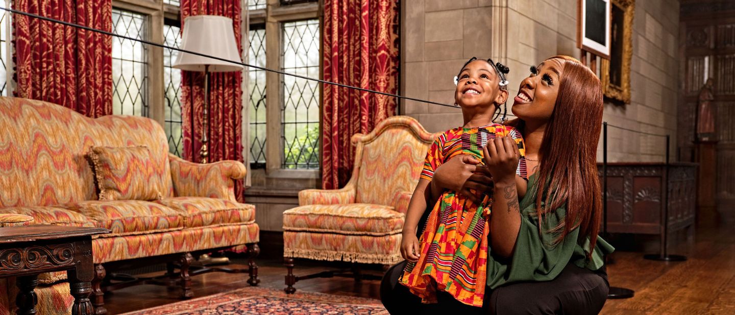 Mother and daughter smiling inside the Main Residence during their House + Grounds Admission visit to Ford House.