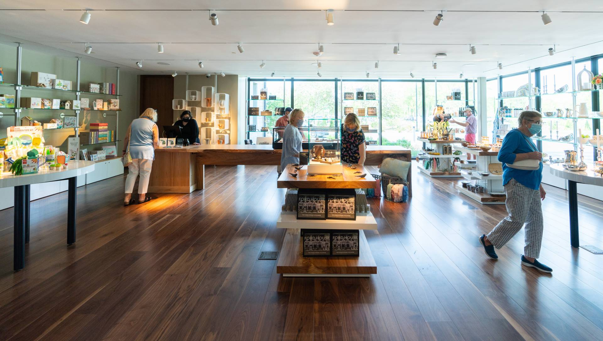 Guests browsing unique gifts, books, and locally inspired merchandise inside The Shop at Ford House, with natural light pouring in from tall windows.