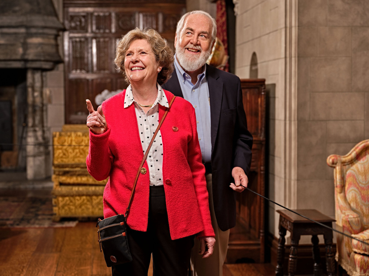 Smiling couple enjoys a guided tour inside the historic Ford House, pointing out architectural details in the Main Residence.