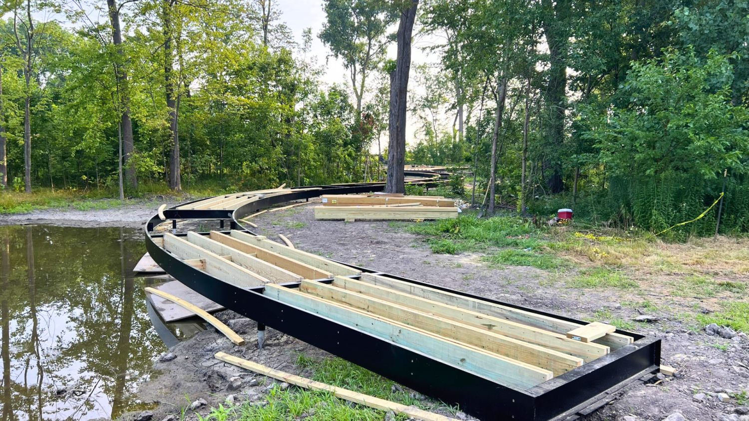 Curved boardwalk under construction in Ford House’s wooded wetland area, part of the Shoreline Restoration Project.