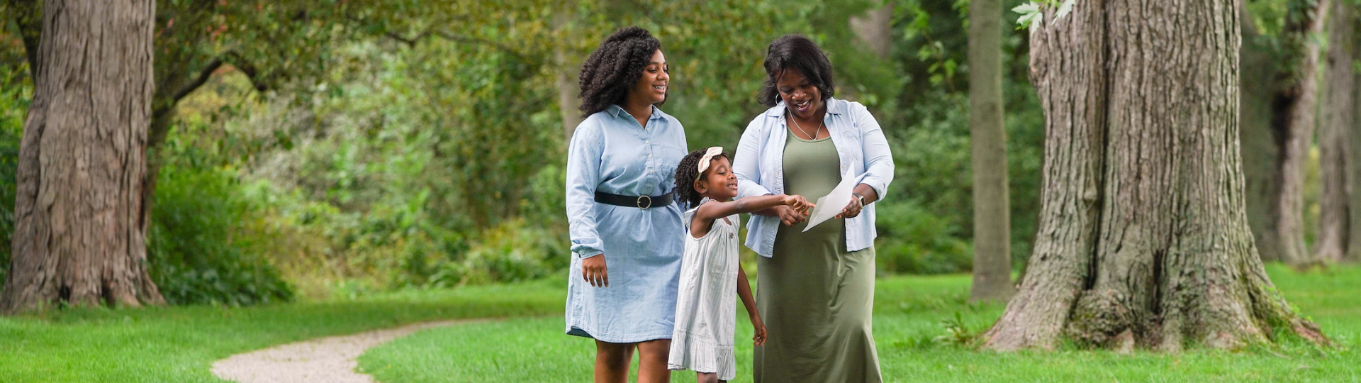 Three generations of Black women smiling as they explore the wooded trail included with Grounds Admission at Ford House.