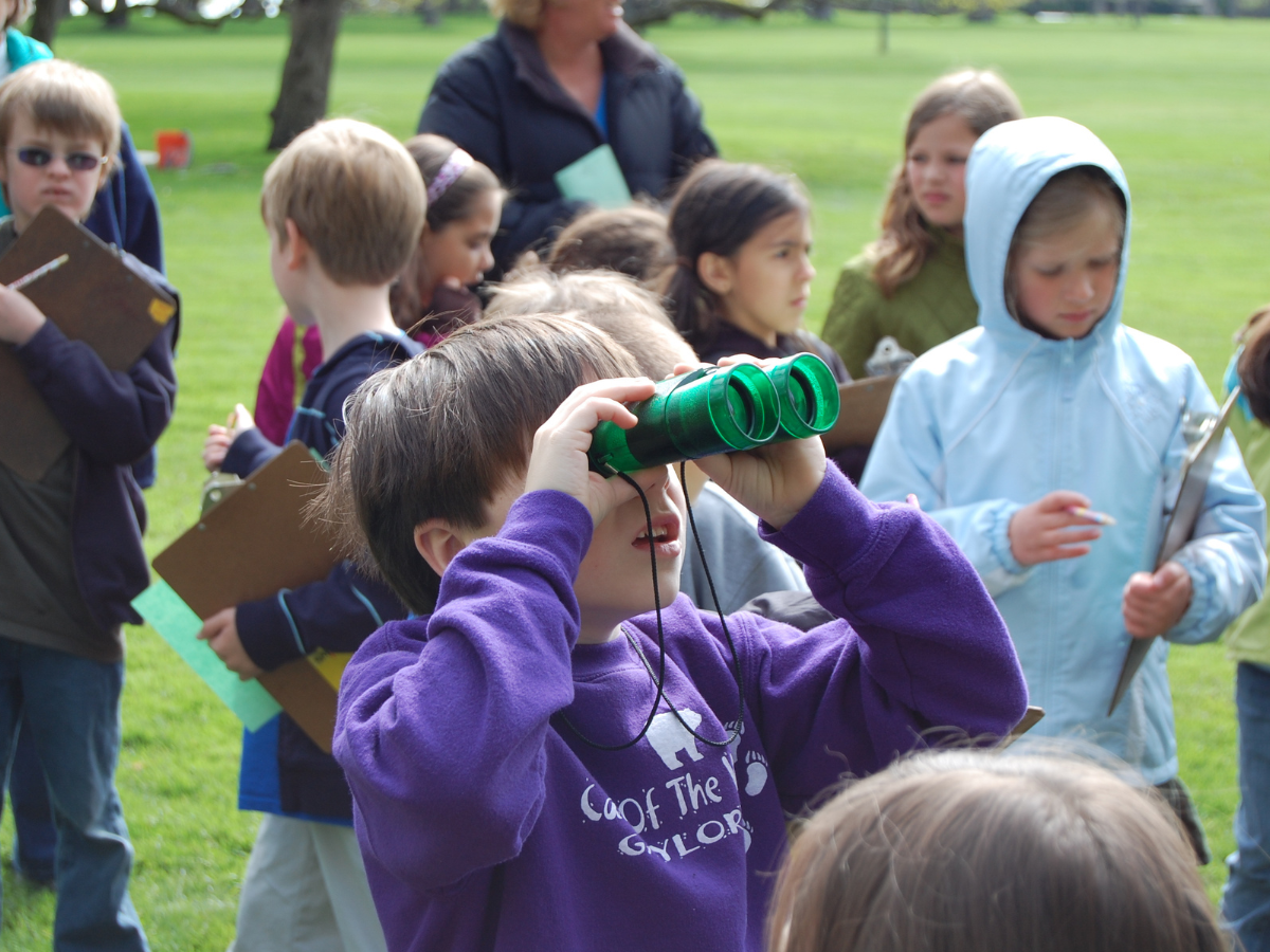 Children participating in a Nature and Outdoor Education Program at Ford House, using binoculars and clipboards to explore wildlife.