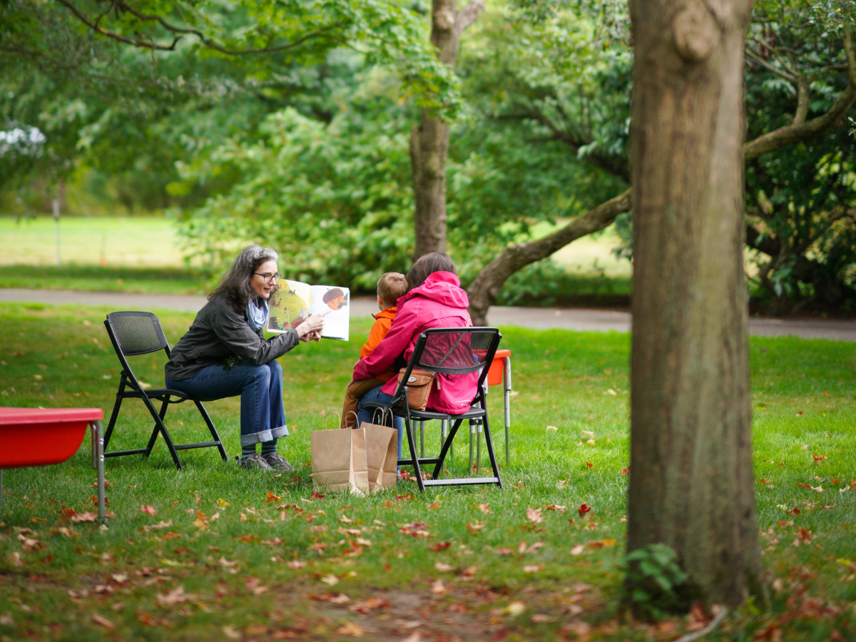 Educator reading a picture book to children outdoors during a Ford House Families & Children Education Program.