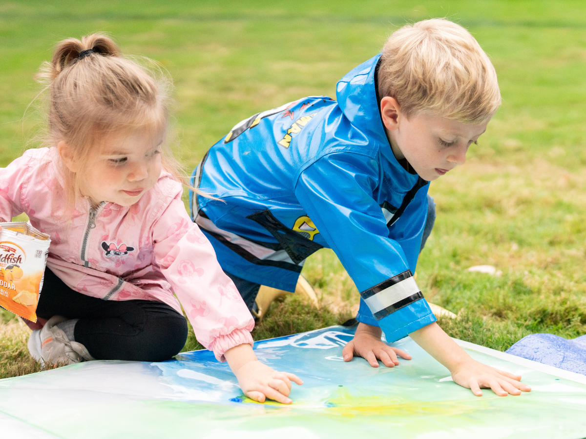 Two children painting together on a large canvas during Story Festival at Ford House.